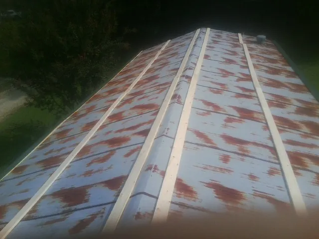 Rusted metal roof panels with new wood purlins before replacement — Storm Damage Roof Repair in Hawk Springs by Roofing Brothers