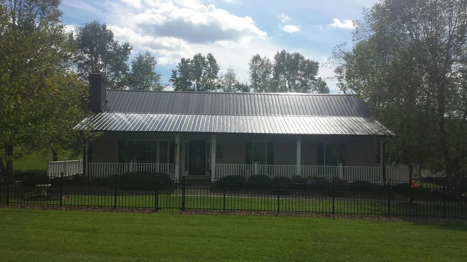 Gray metal roof on a brick ranch with a full width front porch — Gutter Guard Installation work by our crew in Hawk Springs