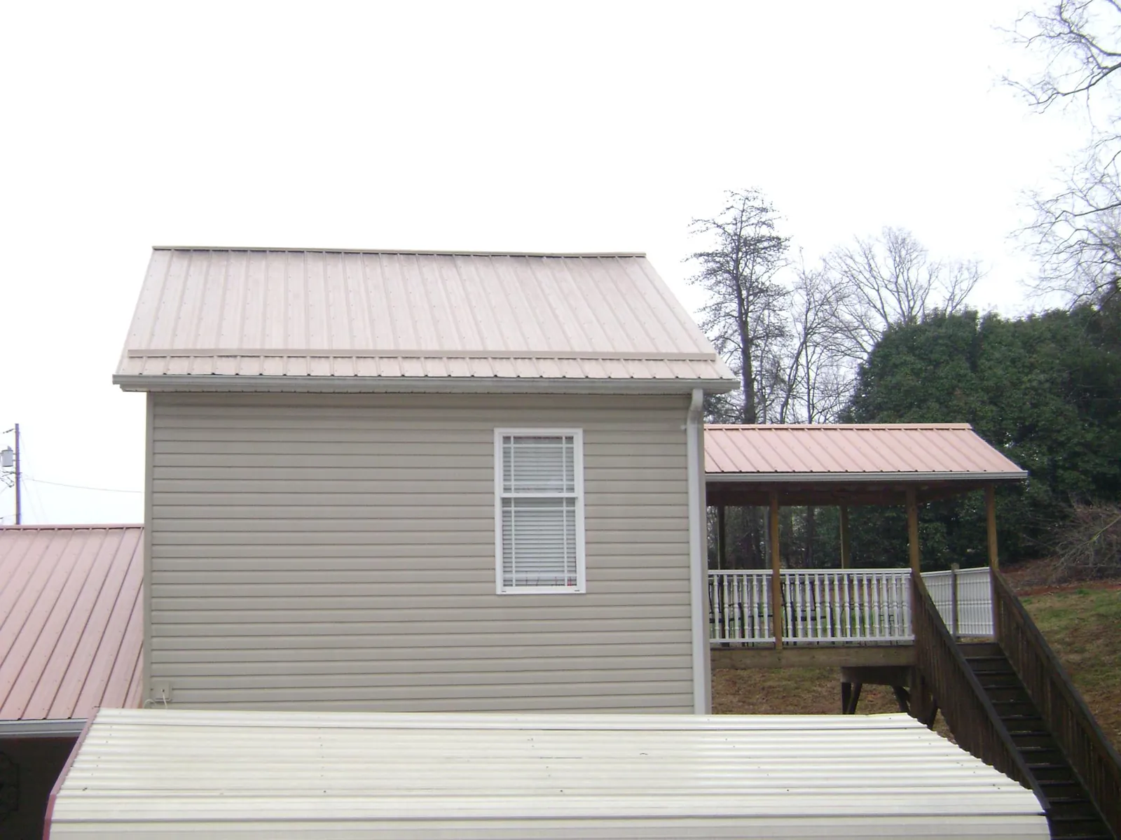 Tan metal roofs on a two story addition and attached porch, from a Roof Replacement job in Hawk Springs