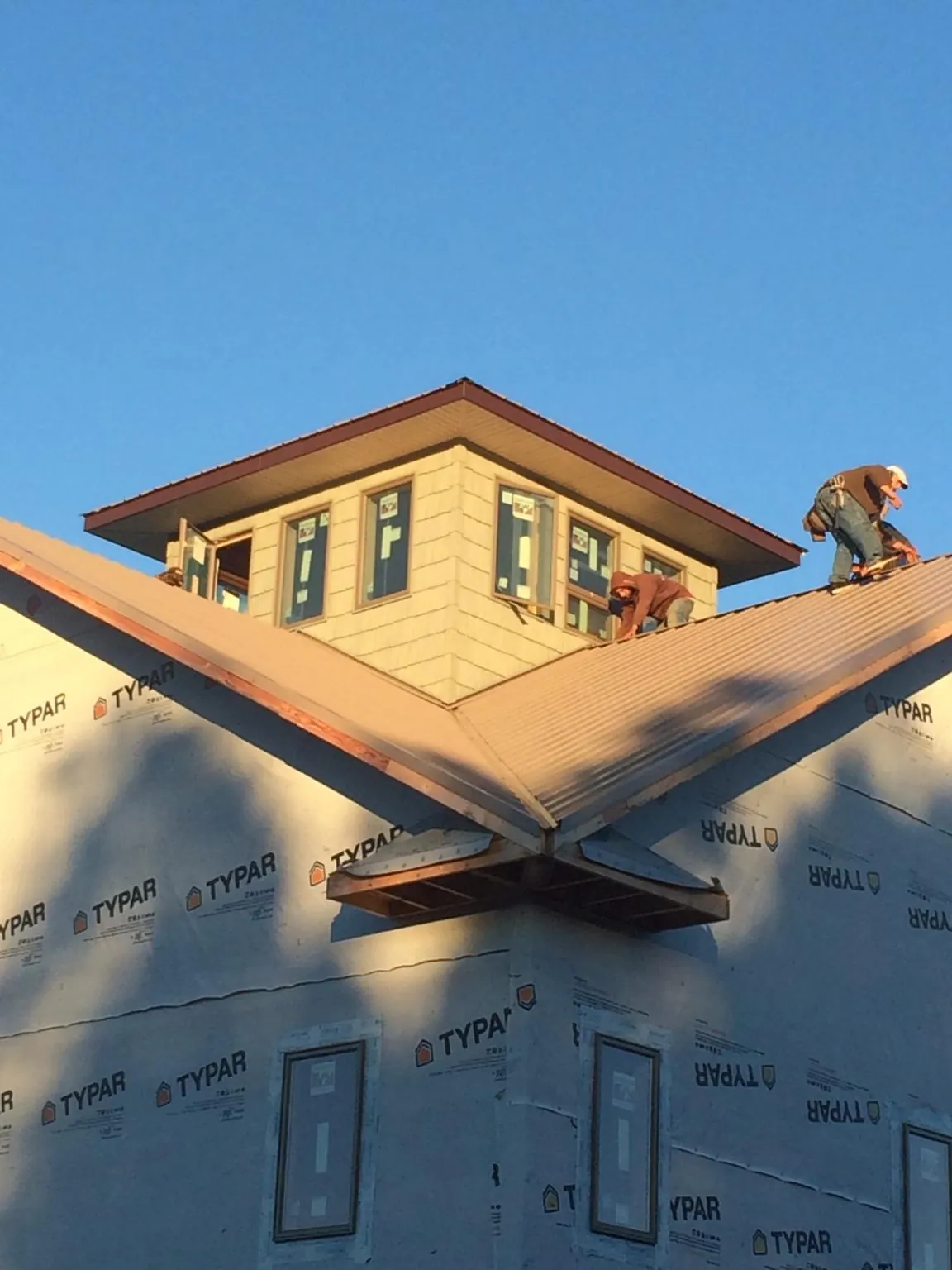 Roofers working around a rooftop cupola on a new metal roof at sunset — Roof Waterproofing in Hawk Springs by Roofing Brothers